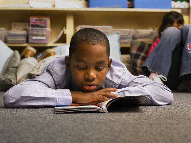 Boy Reading Book in Classroom